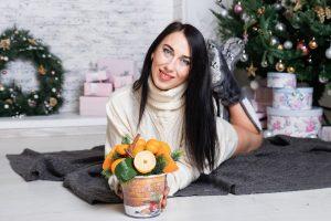 девушка с цитрусами у елки